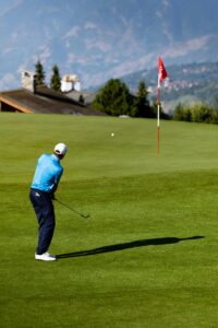 Golfer playing on a picturesque course in Crans-Montana, Switzerland with mountain views.